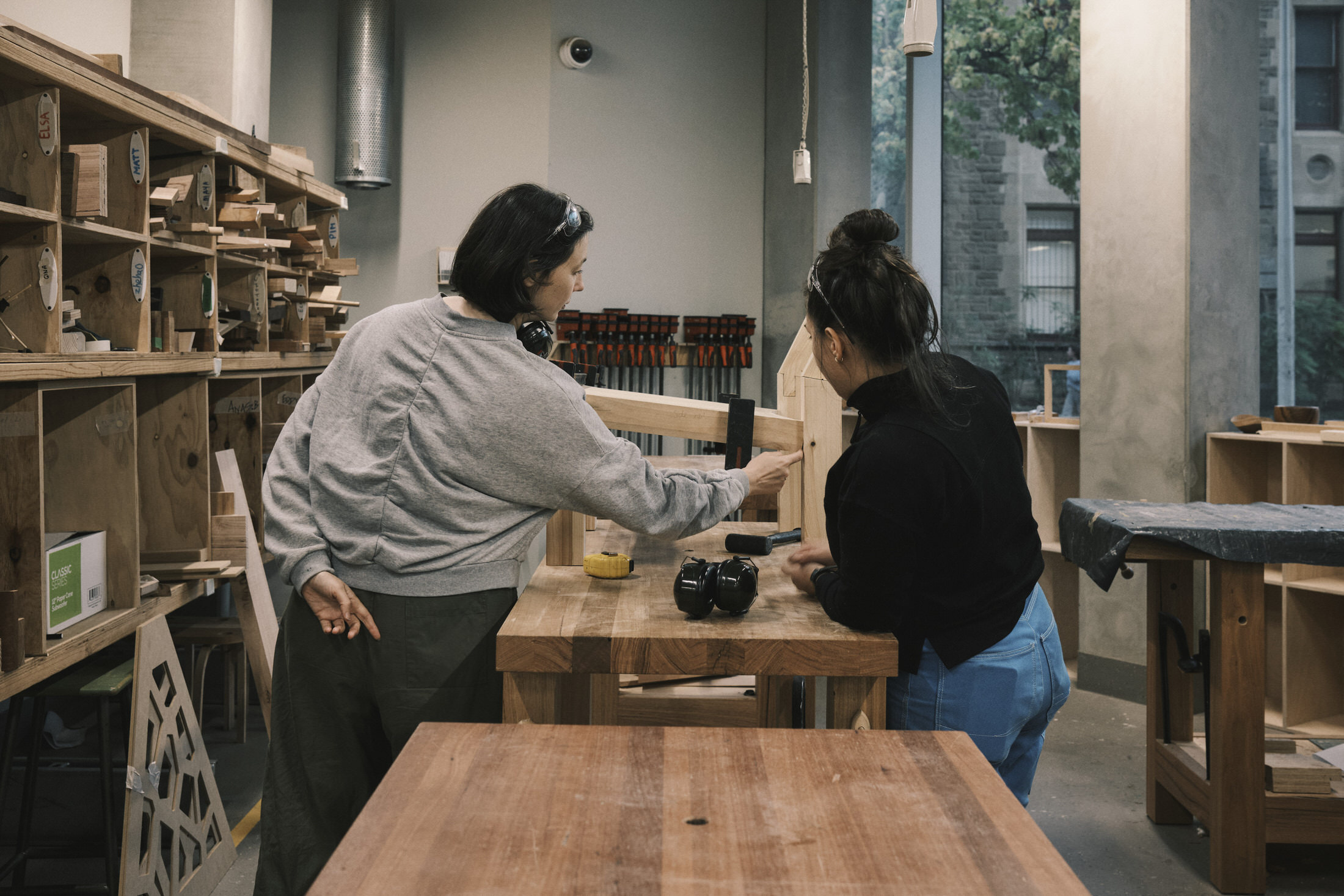 Alexsandra Pontonio working on the wooden chair components in a woodworking studio.