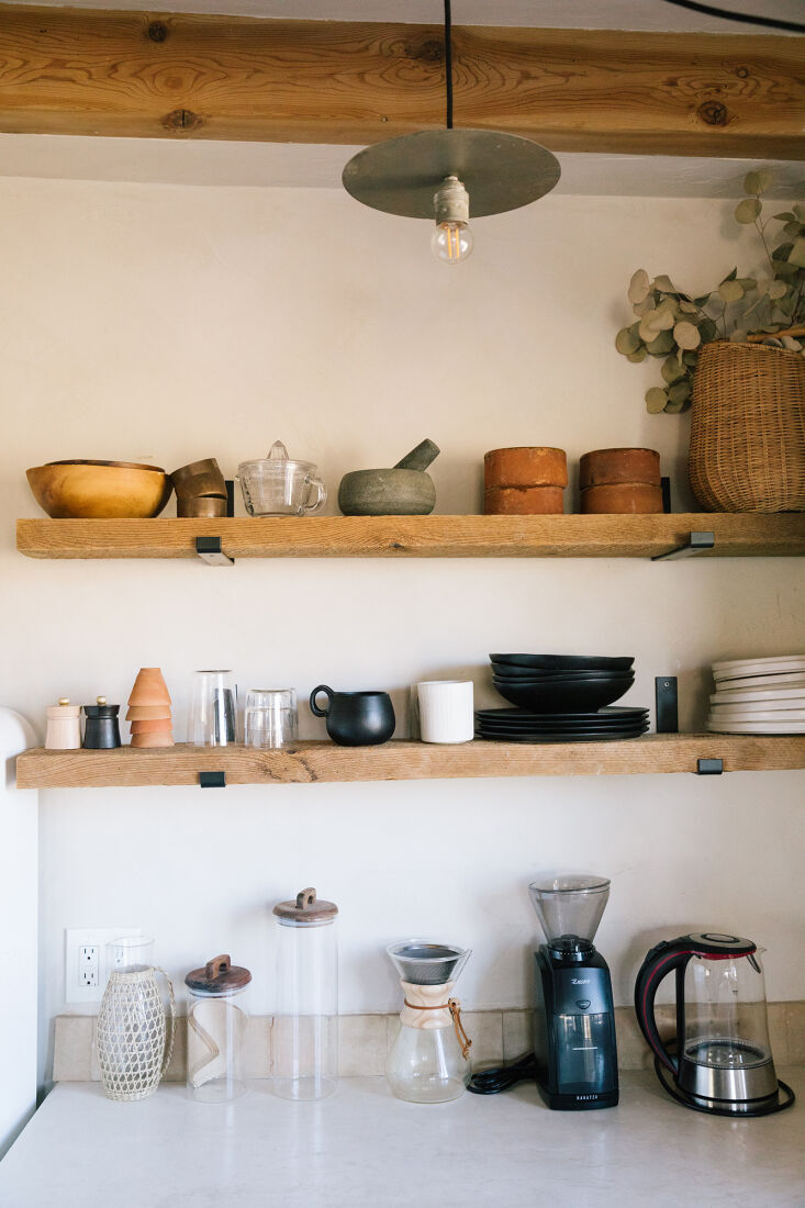 Open floating shelves made from reclaimed antique wood against a white plaster wall.
