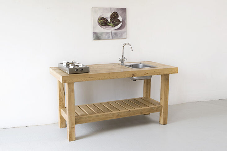 A rustic wooden kitchen island with a small integrated sink and faucet.