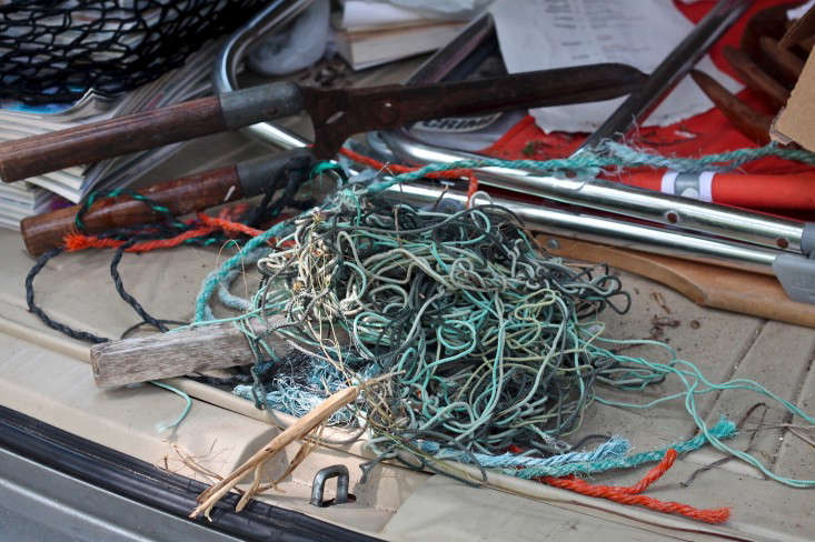 Hands sorting various colors of marine twine into piles on a wooden surface.