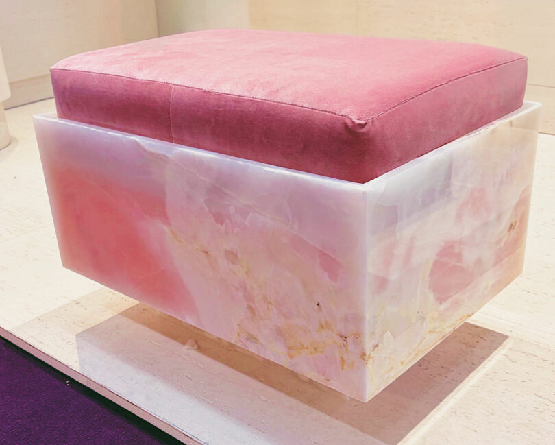 A modern stool featuring a polished pink onyx square base and a matching plush pink velvet cushion.