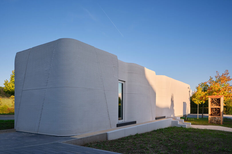 A single-story building featuring smooth, curved exterior walls made of layered concrete.