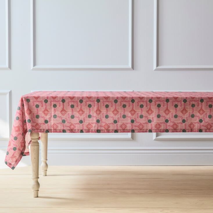 A dining table set with a floral patterned tablecloth and matching napkins.