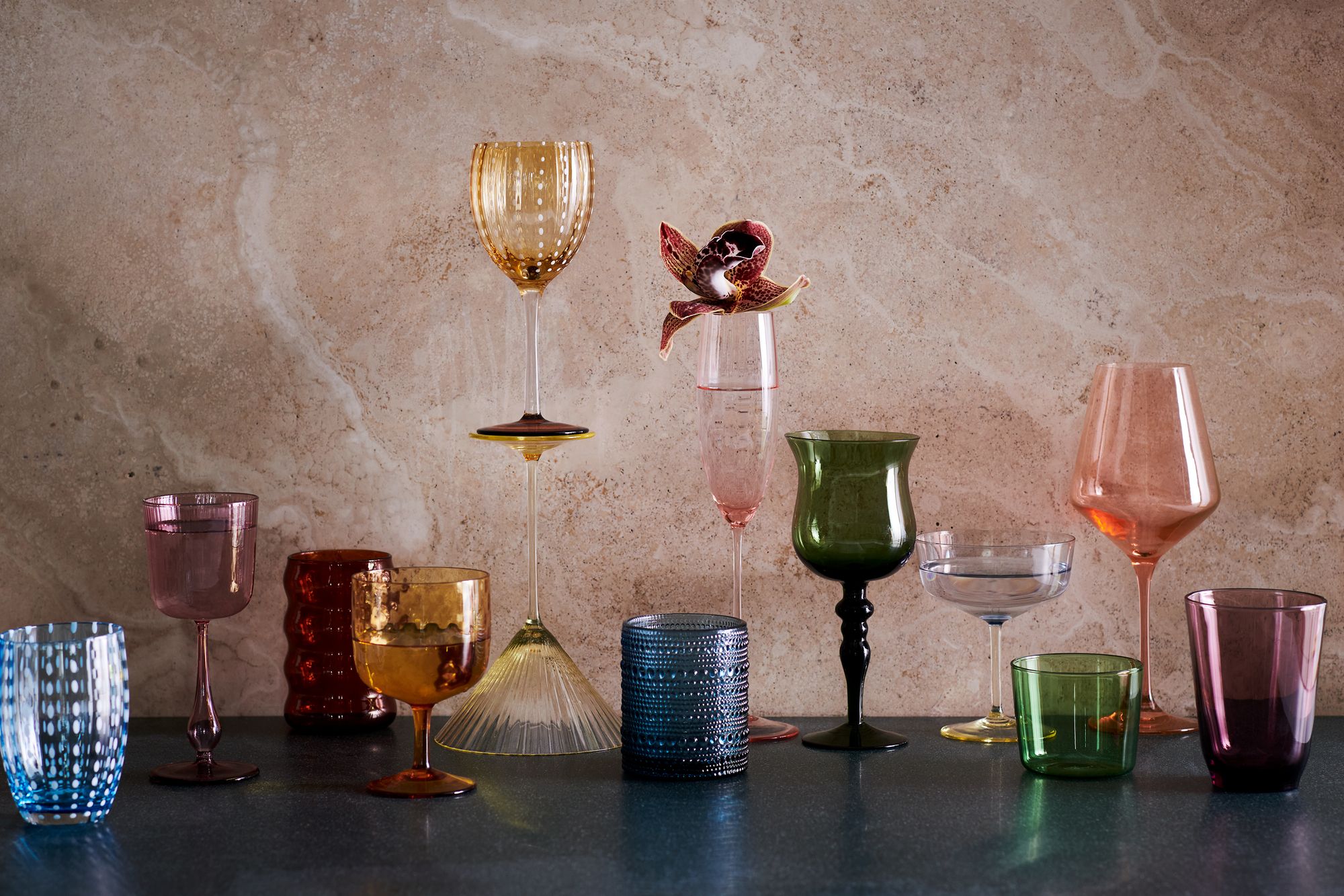 Graphic overlay text 'Shake Up Your Home Bar With These 9 New Glassware Arrivals' set against a backdrop of elegant barware.