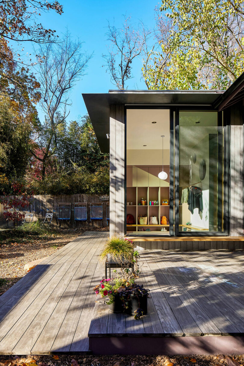 Interior view looking out through large glass doors onto a wooden deck and lush trees.