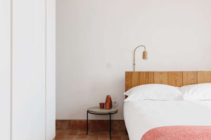 A minimalist bedroom featuring a cork side table and wood panel headboard.