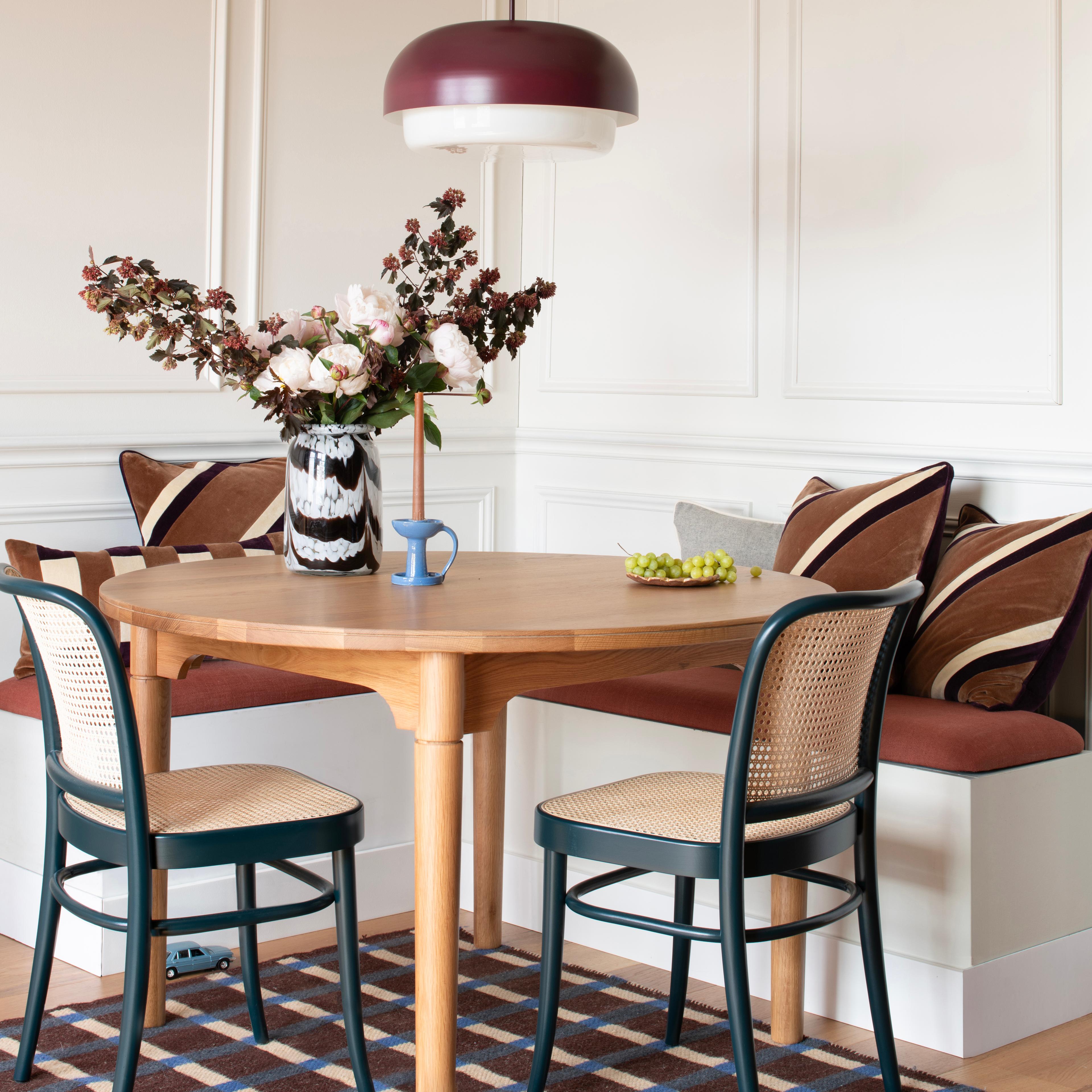 A raisin-colored pendant light hanging over a walnut wood table.