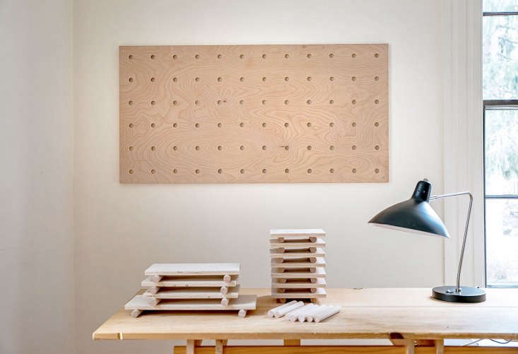 A large DIY pegboard mounted on a wall above a desk, holding tools and decor.