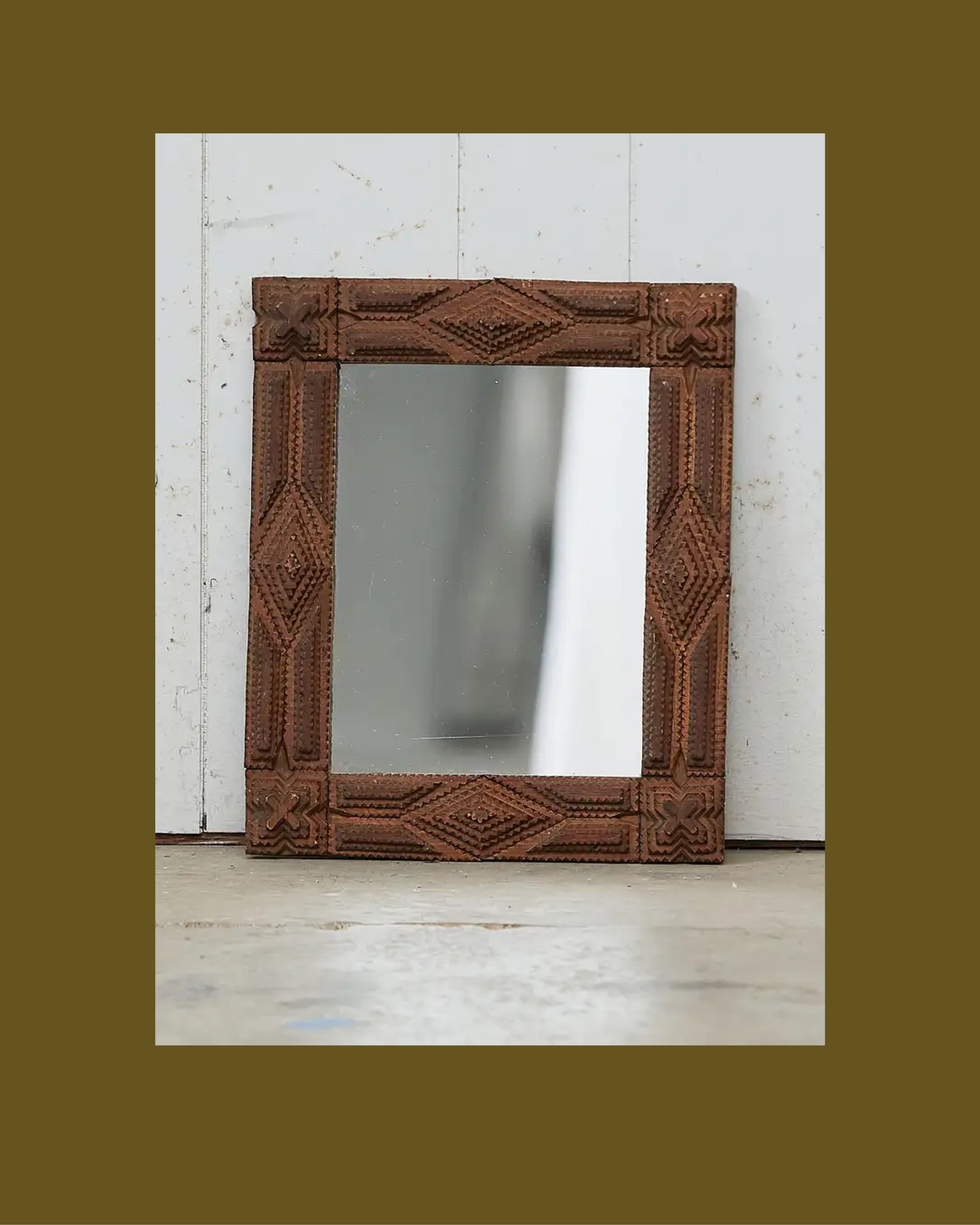 An intricately carved wooden picture frame leaning against a neutral-toned wall.