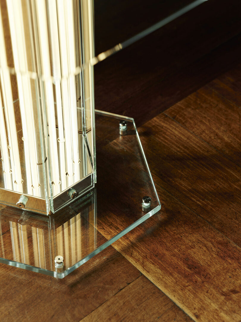 Close-up of a glass hexagonal base with metal bolts supporting a vertical light structure.