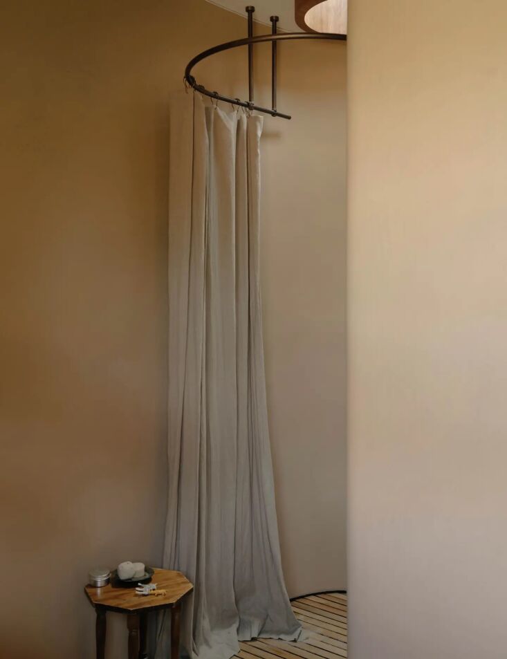 A curved shower room rendered in Tadelakt with a circular skylight overhead showing tree views.