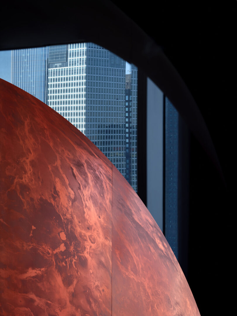 A large red sphere inside a high-rise apartment with the Beijing skyline visible through the window.