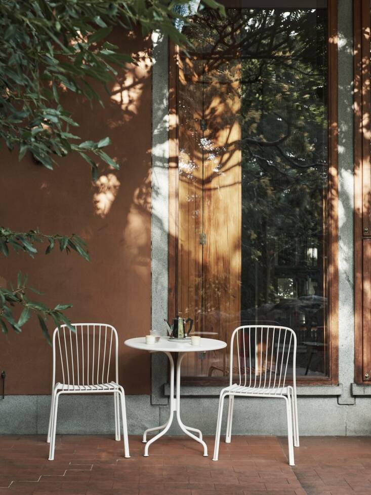 A compact &Tradition Thorvald bistro set including a round table and two chairs in a minimalist garden setting.