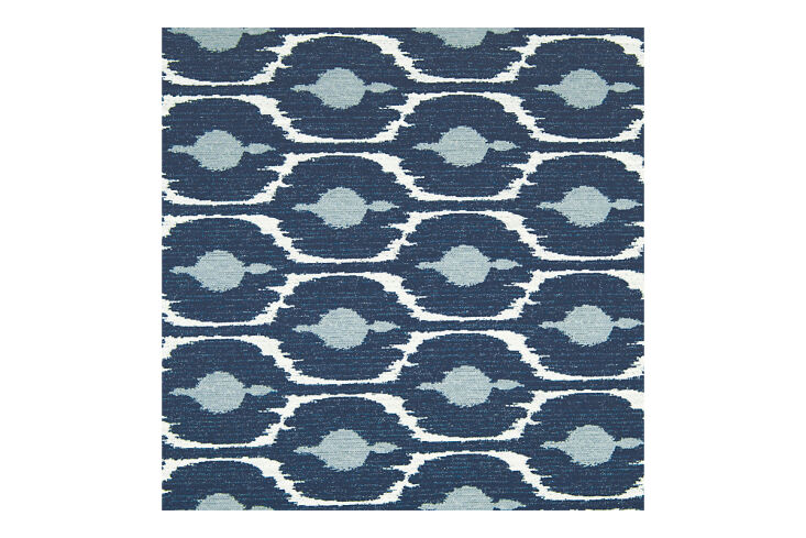 An upholstered headboard with a blue and white ikat pattern.