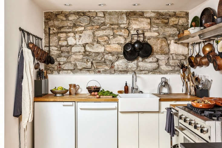 The small kitchen of chef David Tanis featuring open shelving and tools hung neatly on the walls.
