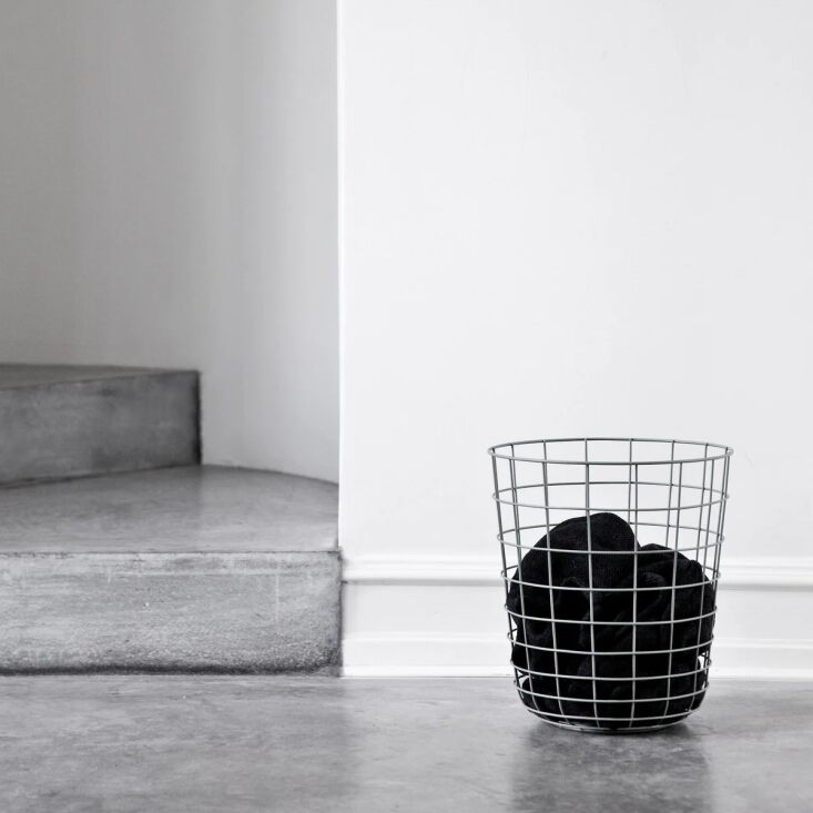 A minimalist black wire frame waste basket with an open-top design.