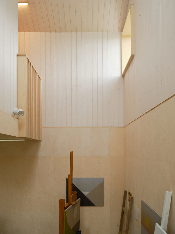 An interior view from a high vantage point looking down into a studio area and across a wooden hallway.