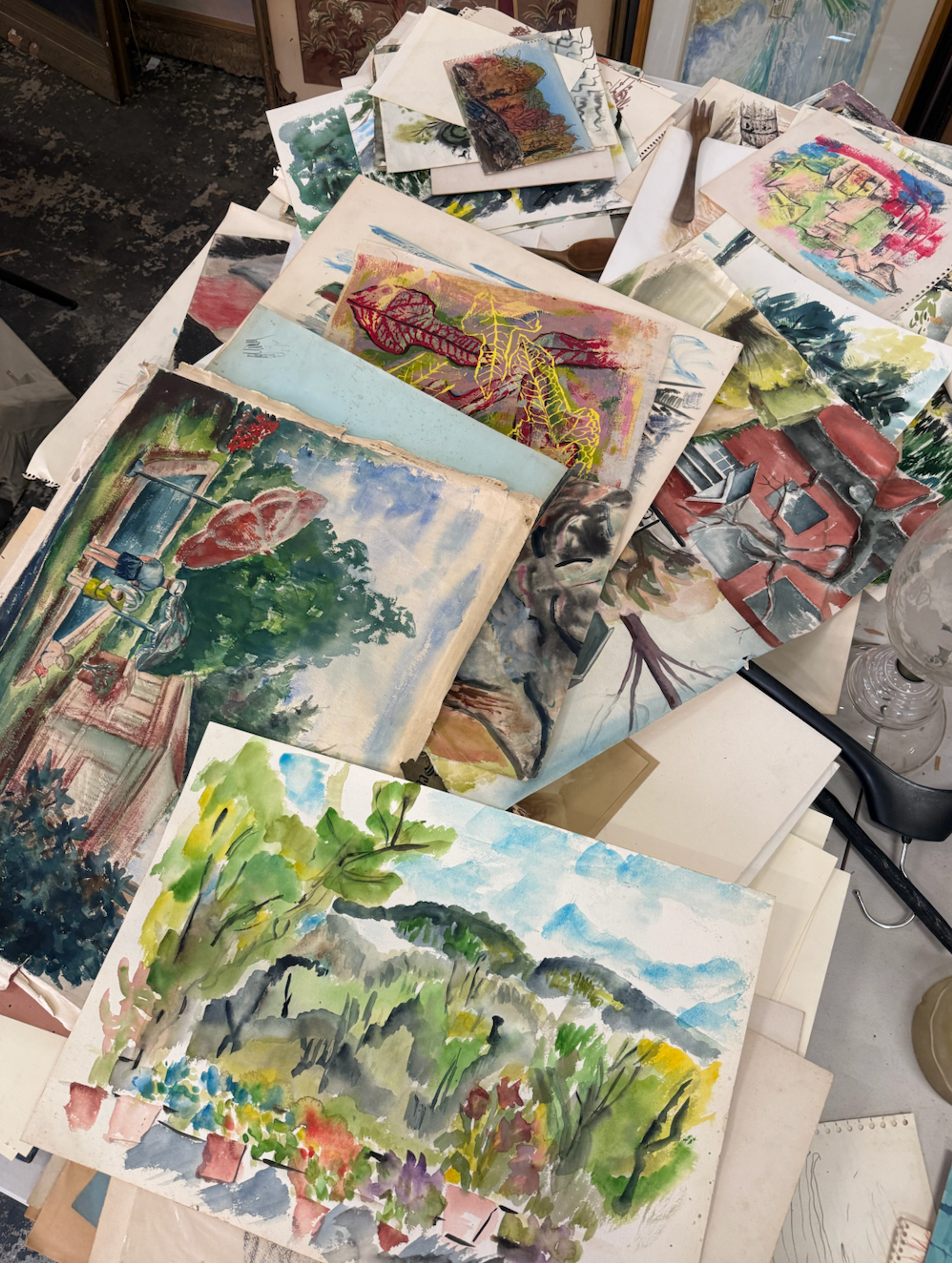 A messy but charming stack of thrifted oil paintings and framed sketches.