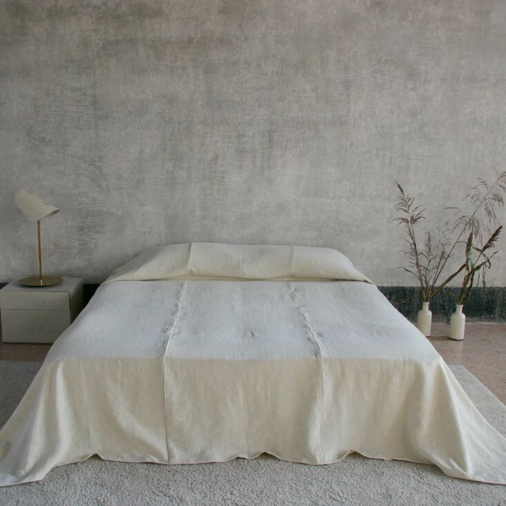 A luxury linen bed cover with contrasting piping details along the edges.