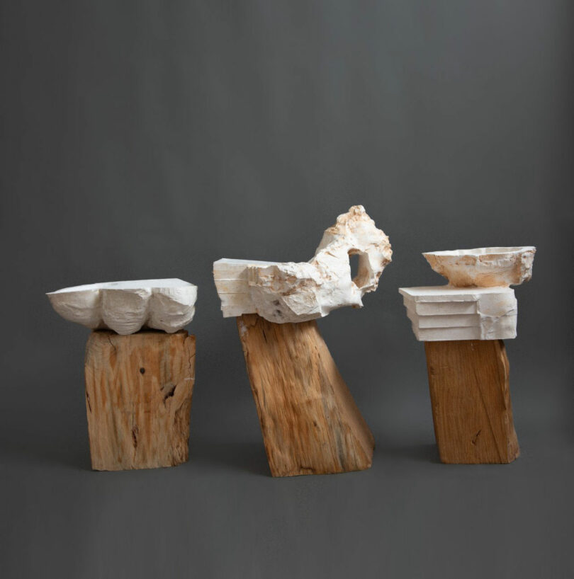 Three abstract sculptures made of wood blocks and textured white plaster.