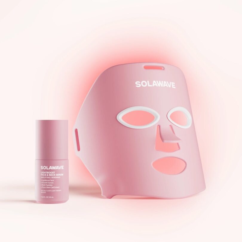 A pink SolaWave LED face mask and a matching serum bottle under a soft pink glow.
