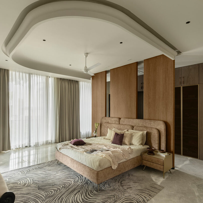 A minimalist master bedroom with neutral tones, a wooden partition, and soft natural light from floor-to-ceiling curtains.