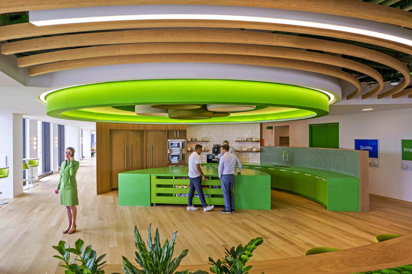 Office kitchen area with a bright green circular light and matching green cabinetry.