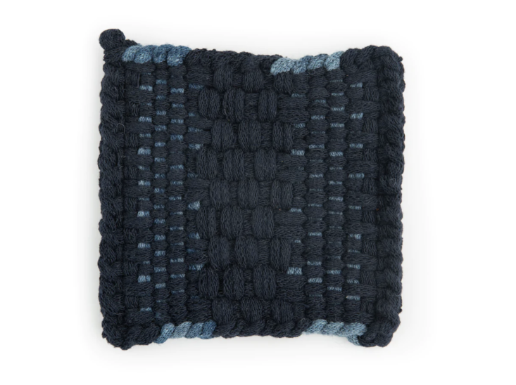 A deep indigo and navy blue hand-loomed potholder with a complex weave.