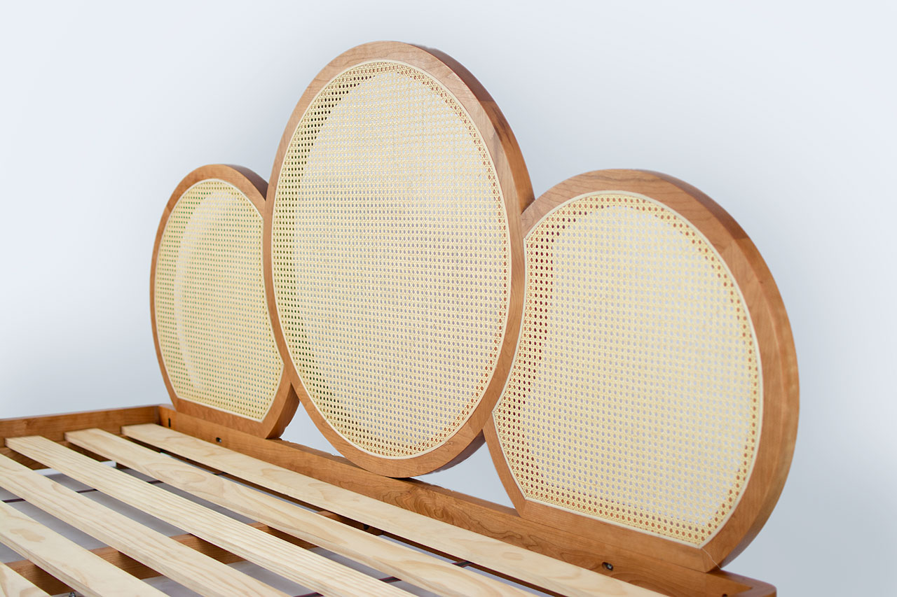 A sustainable organic mattress paired with a biophilic woven cane headboard in a bright room.