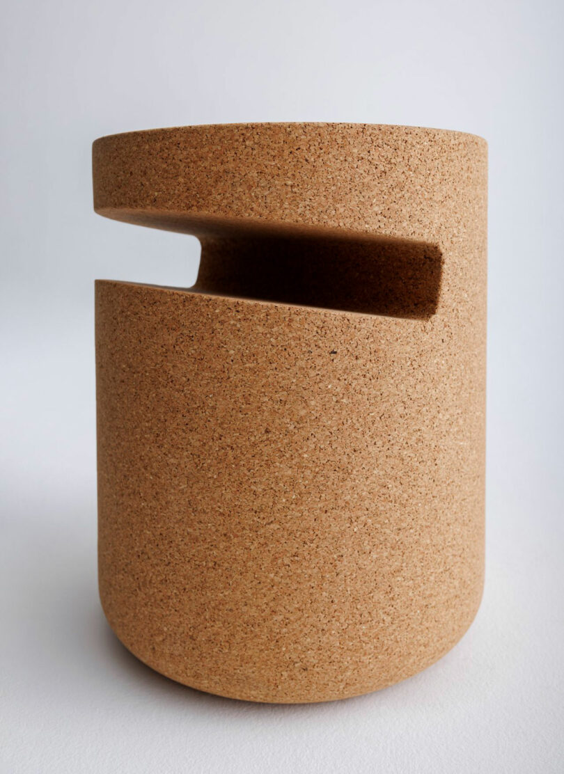 Close-up of a cylindrical cork side table featuring a precise horizontal cutout near the top.