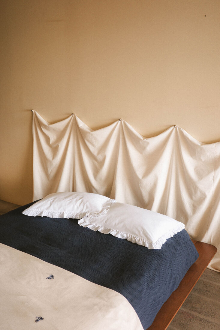 A minimalist bed setup with color-blocked fabric and ruffled pillowcases.