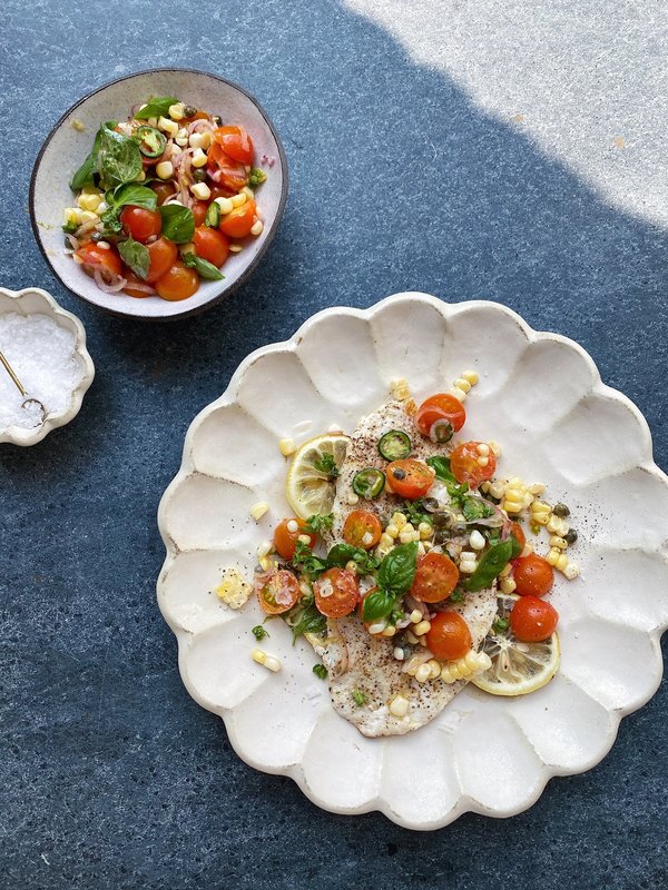 Grilled white fish fillets with visible sear marks served with a charred lemon half.