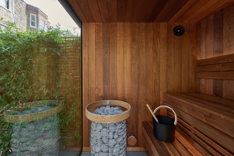 Interior view of a wooden sauna with a large window looking out onto greenery.