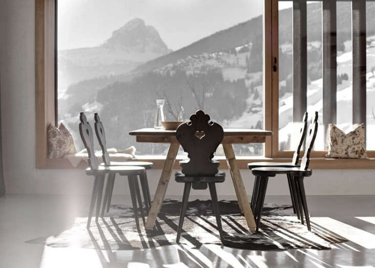 Traditional Tyrolean chairs surrounding a modern dining table in an Alpine holiday house by Pedevilla Architects.