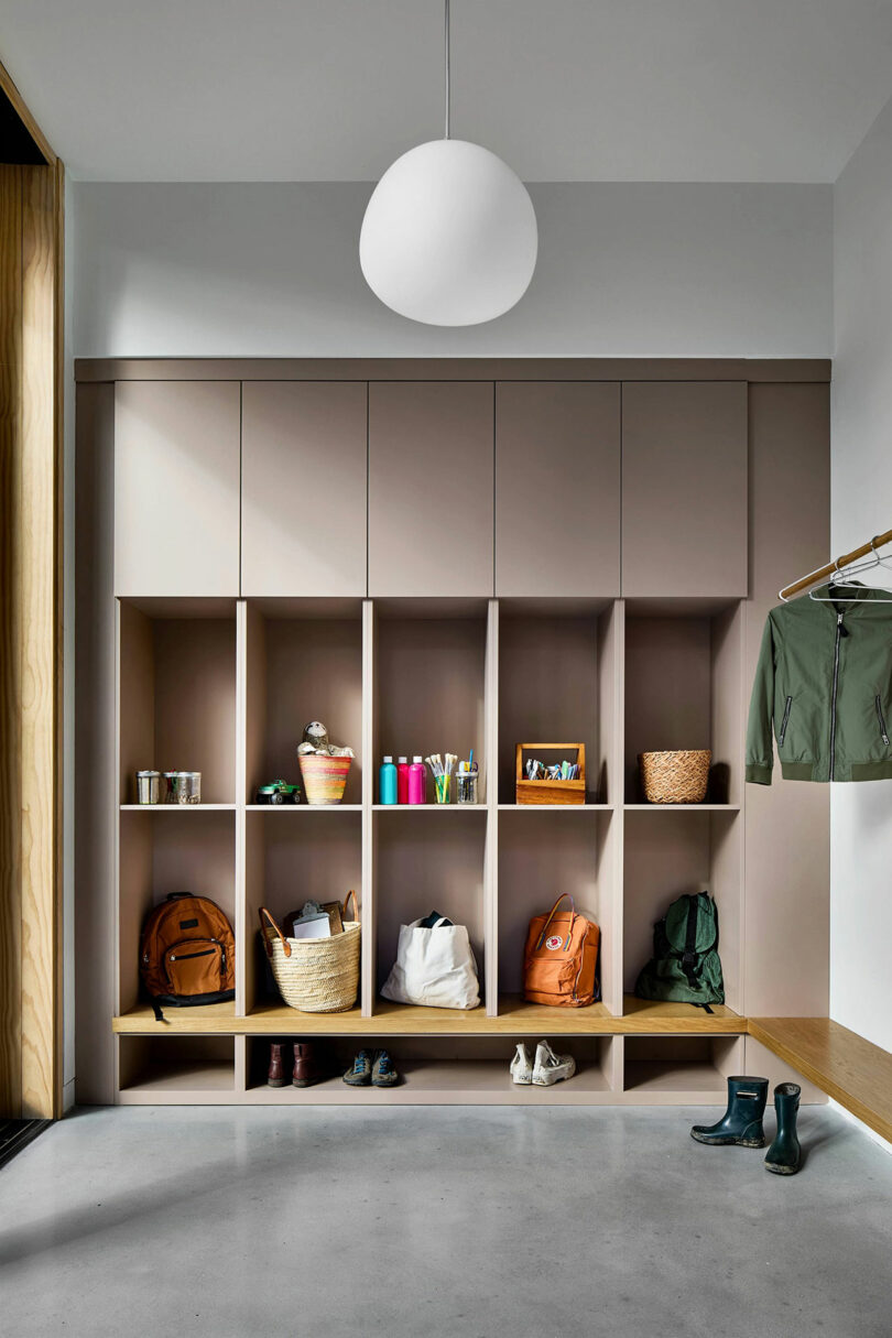 A modern mudroom featuring organized wooden cubbies for bags, shoes, and coats.