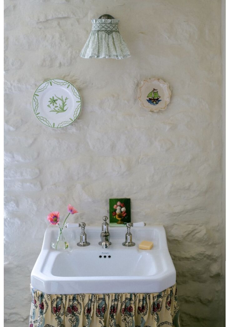 A traditionally pleated floral sink skirt in a classic English barn setting.