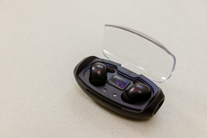 Pair of black SleePods in a transparent lid charging case showing battery percentage.