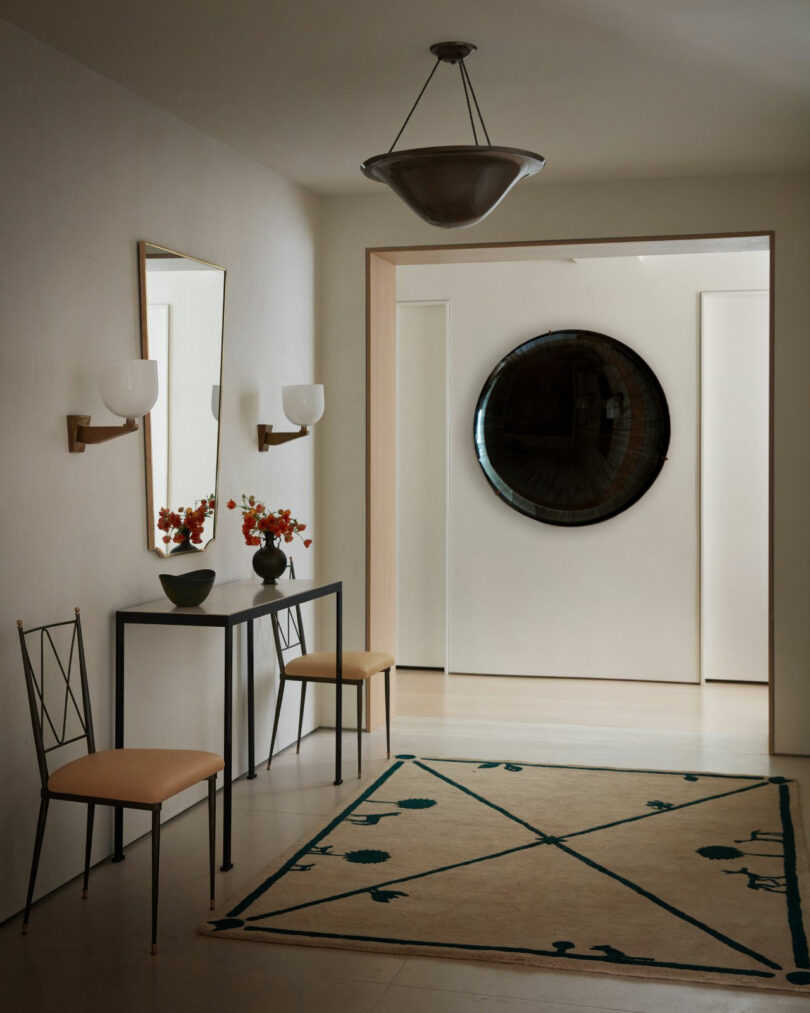 A minimalist hallway with a round mirror, console table, and geometric rug.