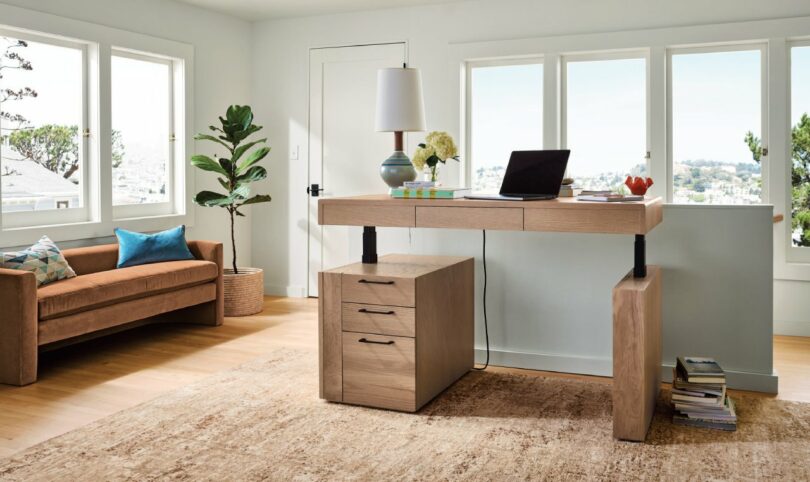 The Lincoln desk in its raised standing position near a large window in a modern home office.