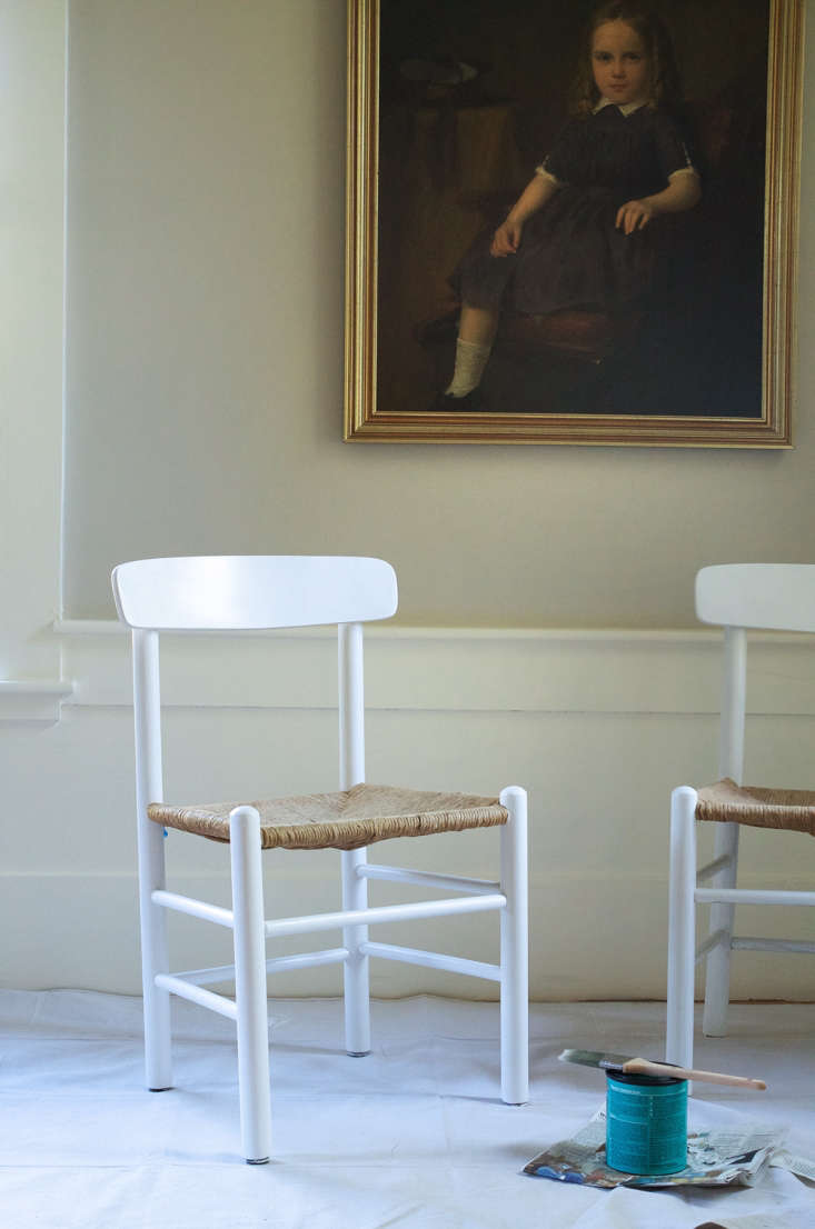 Two fully refurbished chairs with grey paint and new upholstery standing in a dining room.