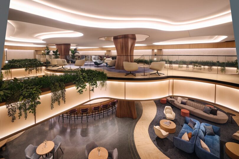A modern airport lounge with circular seating, tiered levels, and integrated indoor plants.