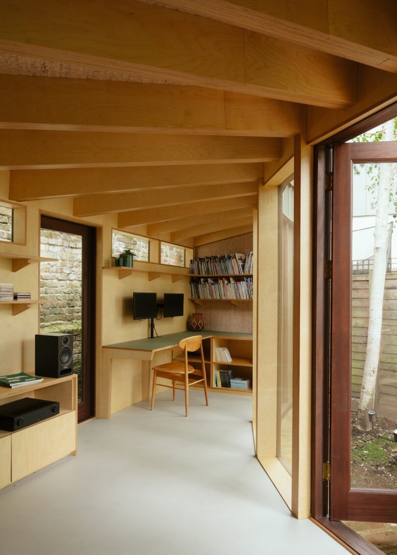 An interior garden office view looking out through an open door at birch trees in the backyard.