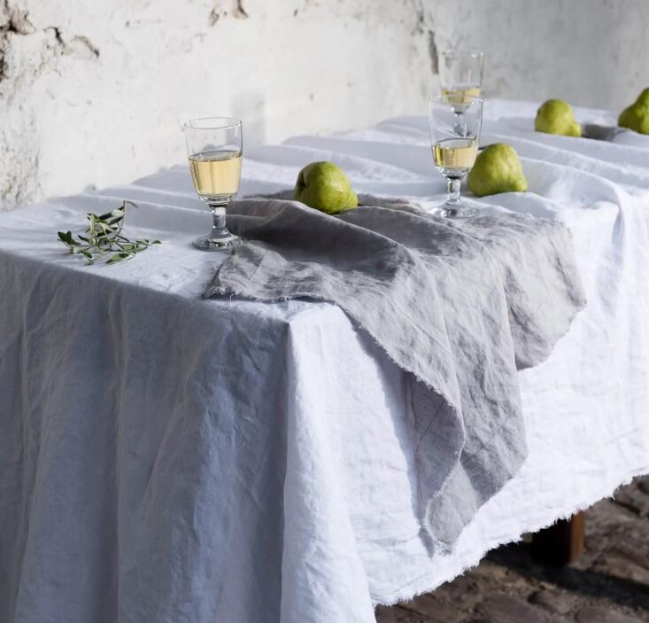 Hand-frayed grey linen napkins placed on a dinner plate with a rustic finish.