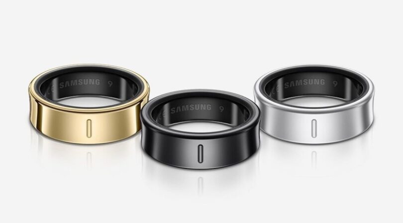 Three sleek smart rings in gold, black, and silver finishes displayed on a white background.
