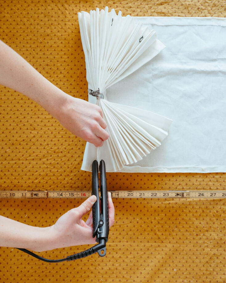 Using a hair straightener to press sharp creases into the fabric folds.