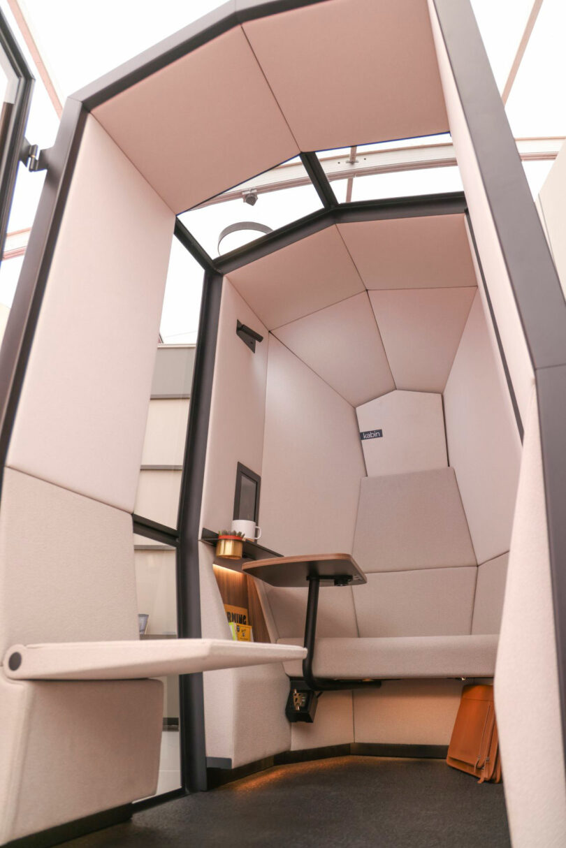 A two-person Kabin private office pod with facing cushioned seats and a central small table.