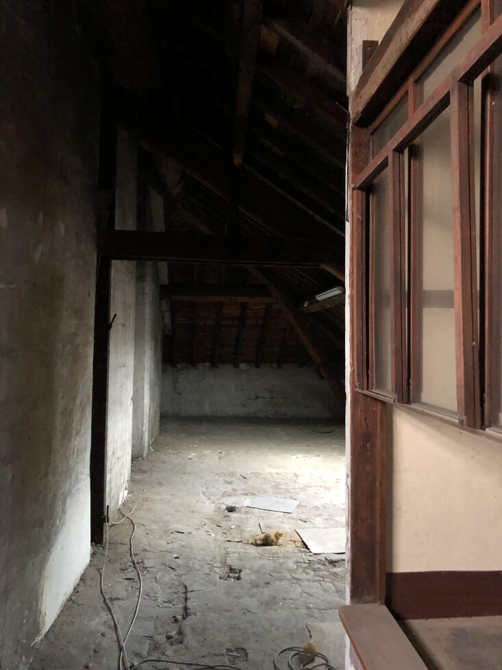 Unfinished 19th-century attic carpentry workshop with exposed timber beams and debris.