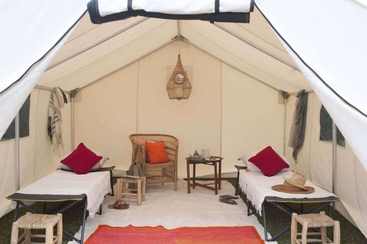 Full view of a canvas tent interior with Peruvian rugs, camp cots, and Moroccan furniture.