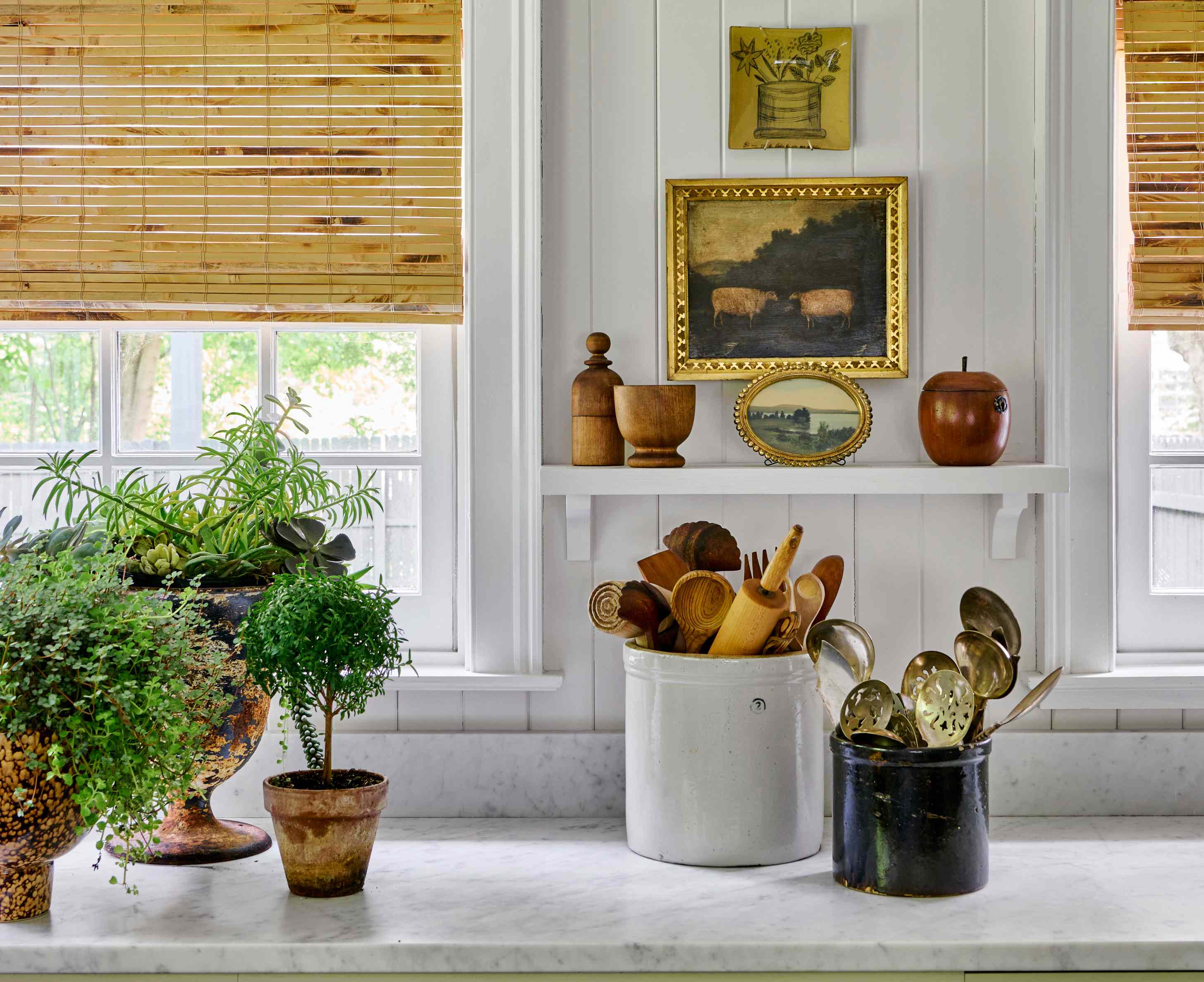 A minimalist kitchen corner featuring marble surfaces, shiplap walls, and vintage wooden kitchen utensils in a ceramic jar.