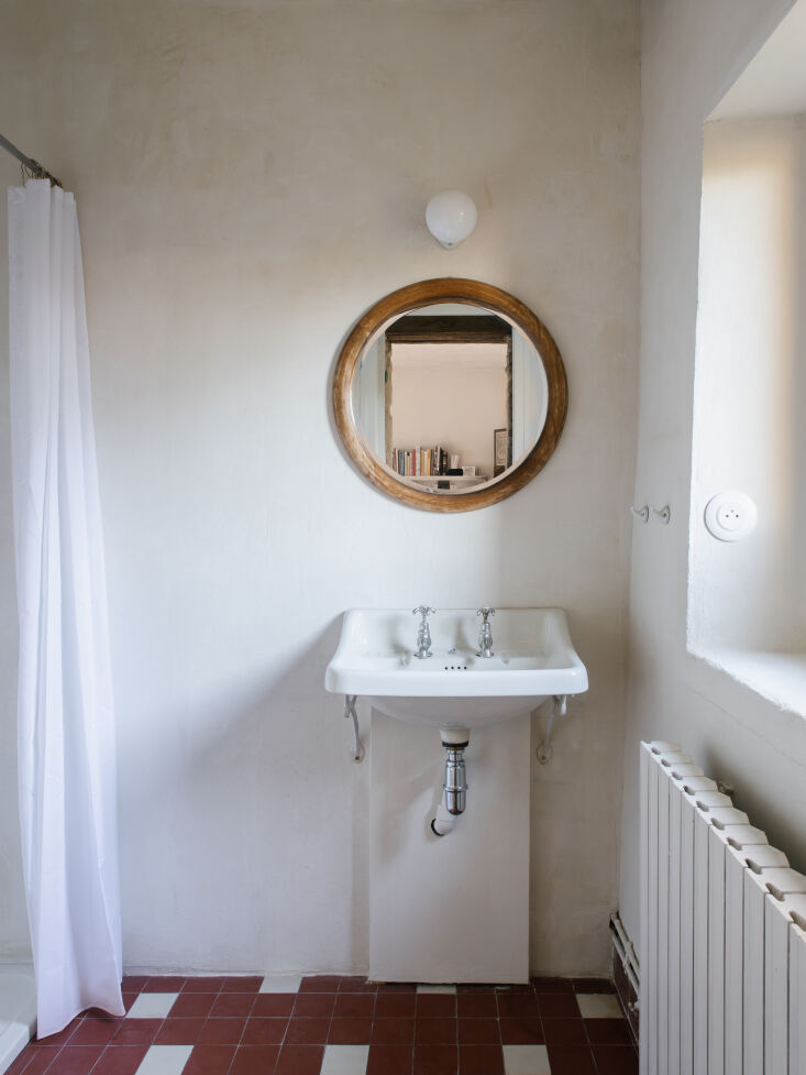 A vintage 1950s ceramic sink and 1970s floor tiles in a restored bathroom space.